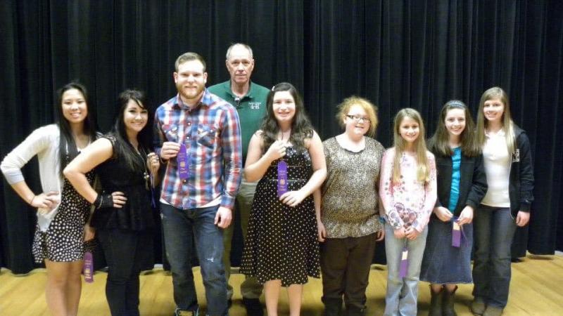 Mr. Cox and 8 student winners from a communication day several years ago. 